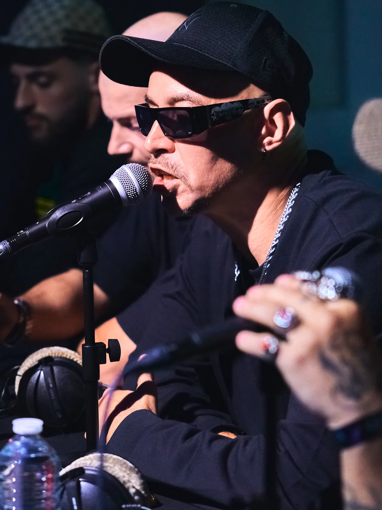 Rappeur en casquette et lunettes noires au micro, entouré des autres participants, Block Mulhouse